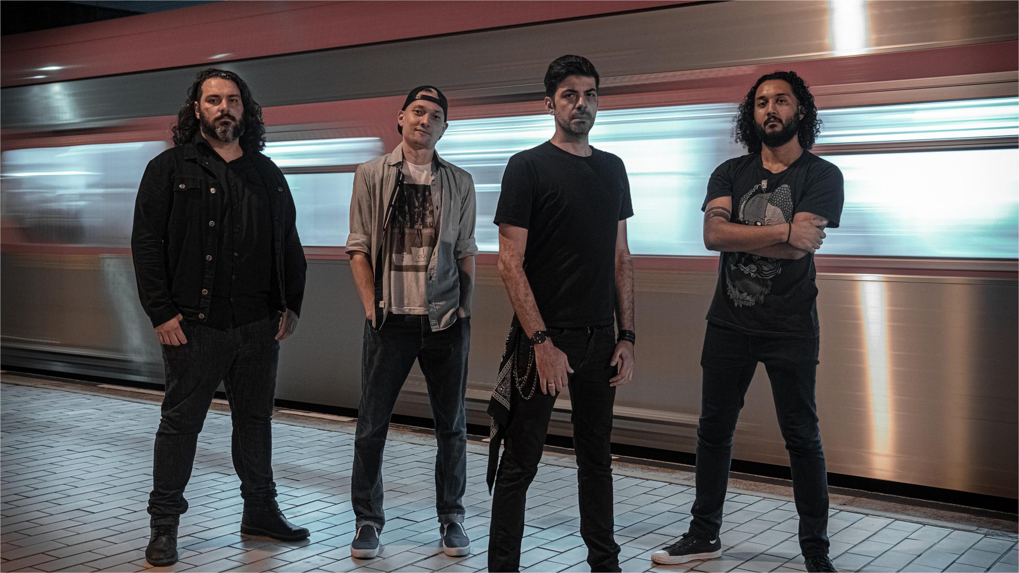 Os quatro integrantes da Demophobia em pé diante de um trem em movimento